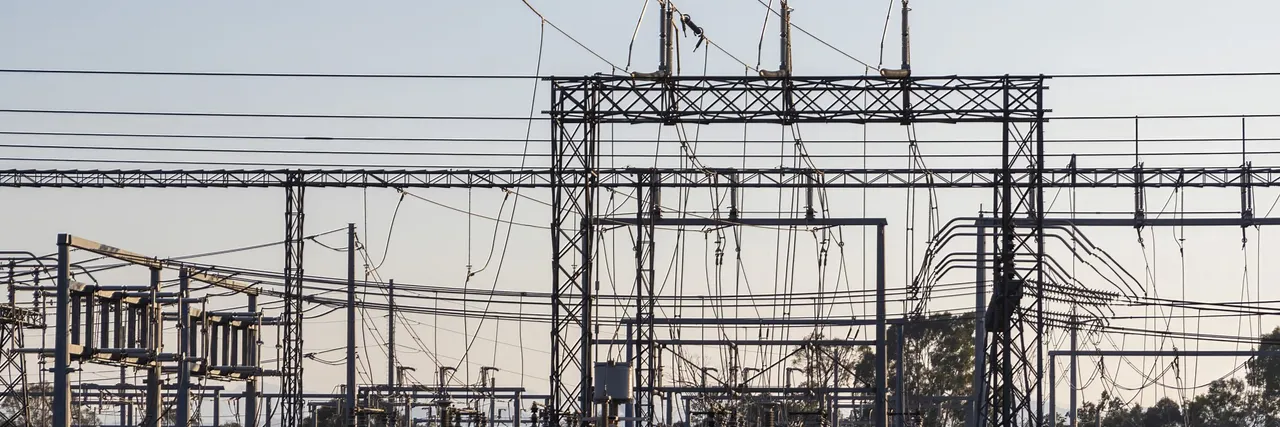 High-voltage electrical substation with steel lattice structures and power lines at dawn