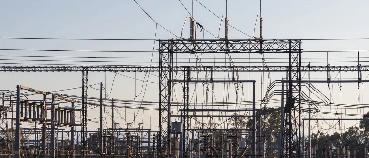 High-voltage electrical substation with steel lattice structures and power lines at dawn