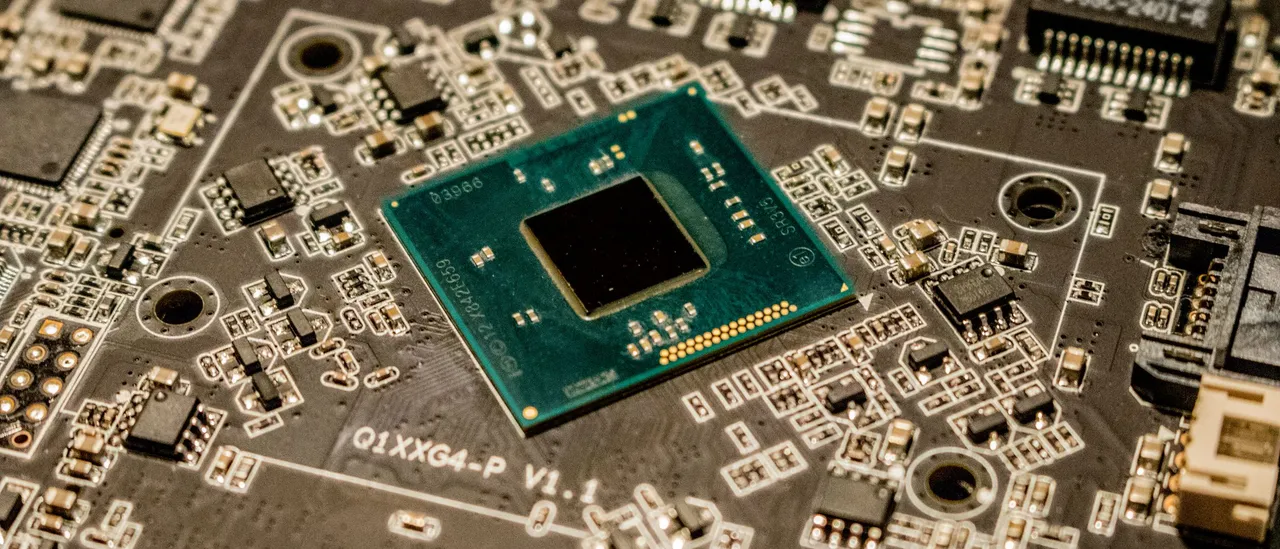 Close-up of a bare processor die mounted on a densely populated circuit board