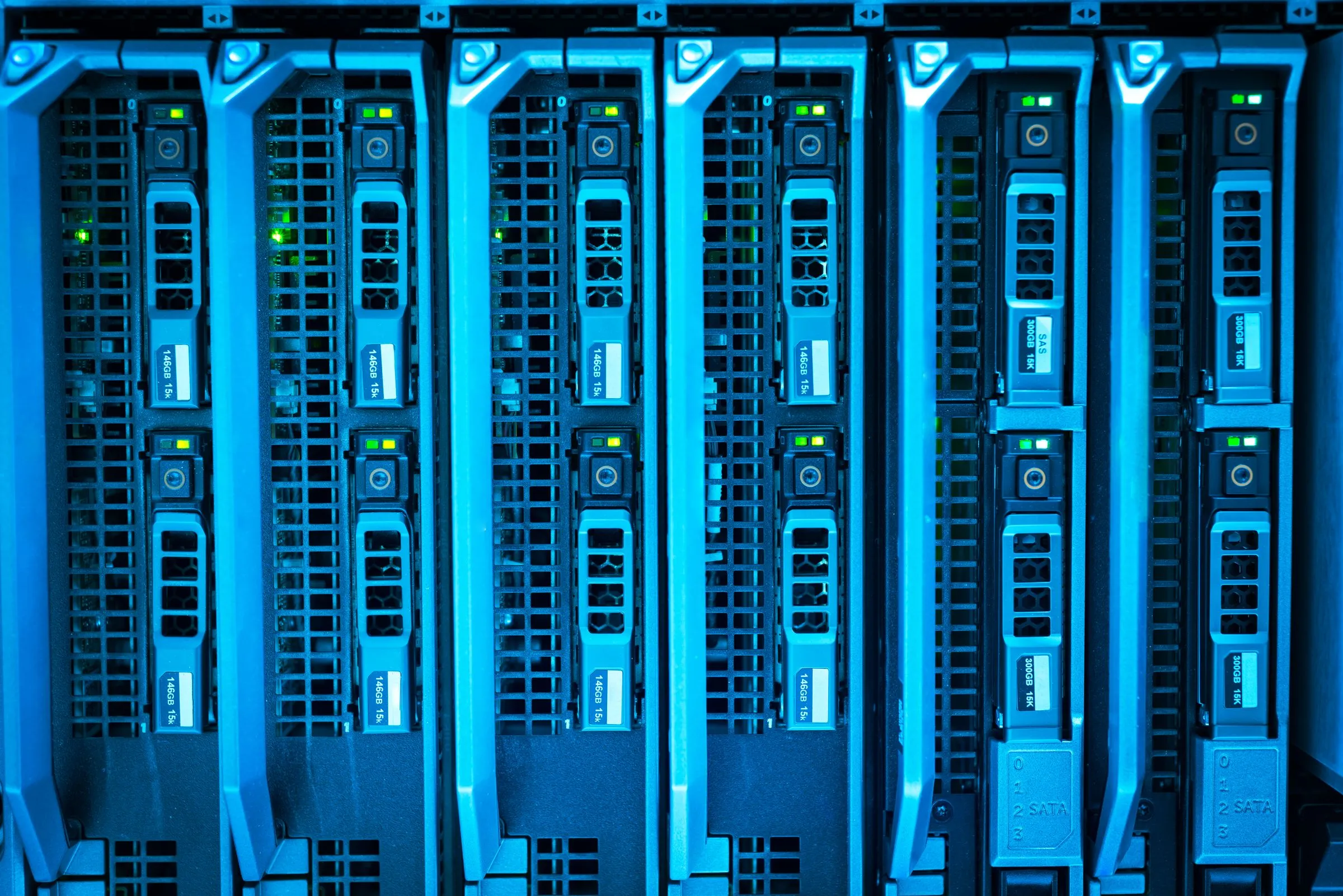 Front of a server chassis with six blade servers in a row, each showing green and amber status lights and drive carriers, lit in blue