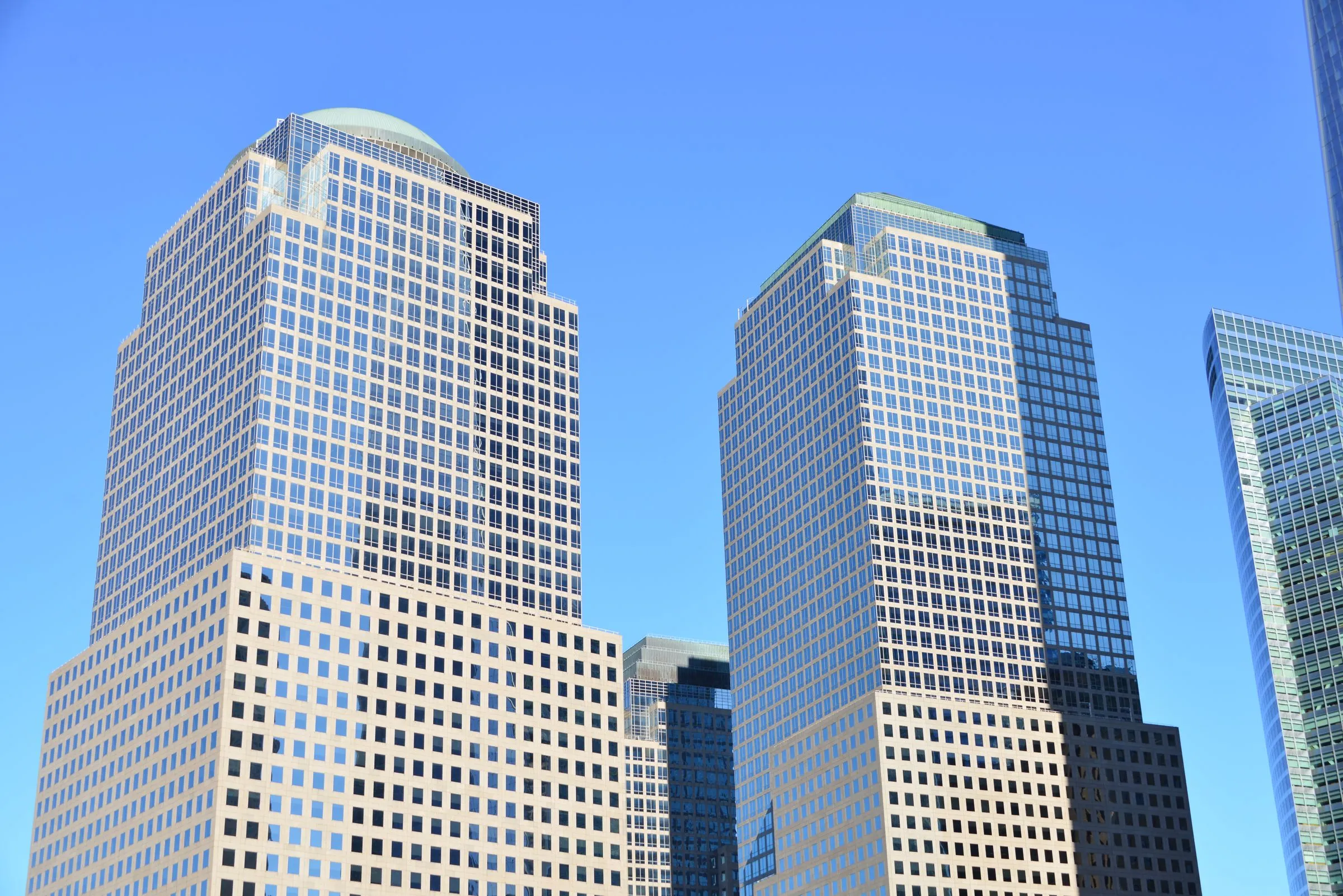 Glass and granite office towers rising against a clear blue sky in a downtown financial district