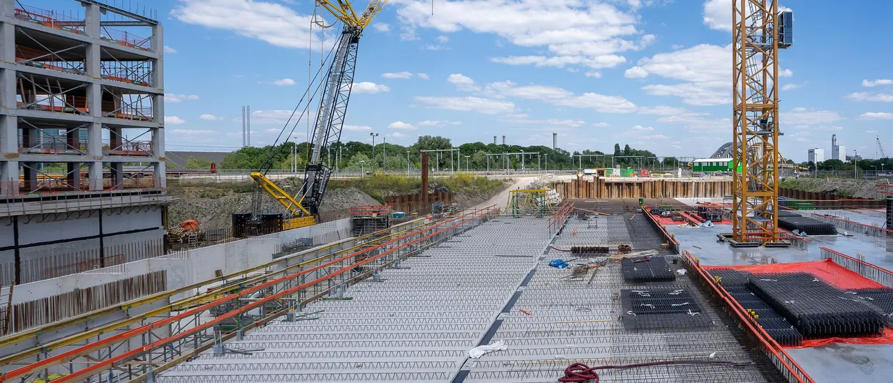 Construction cranes rising over a vast concrete deck at a large construction site