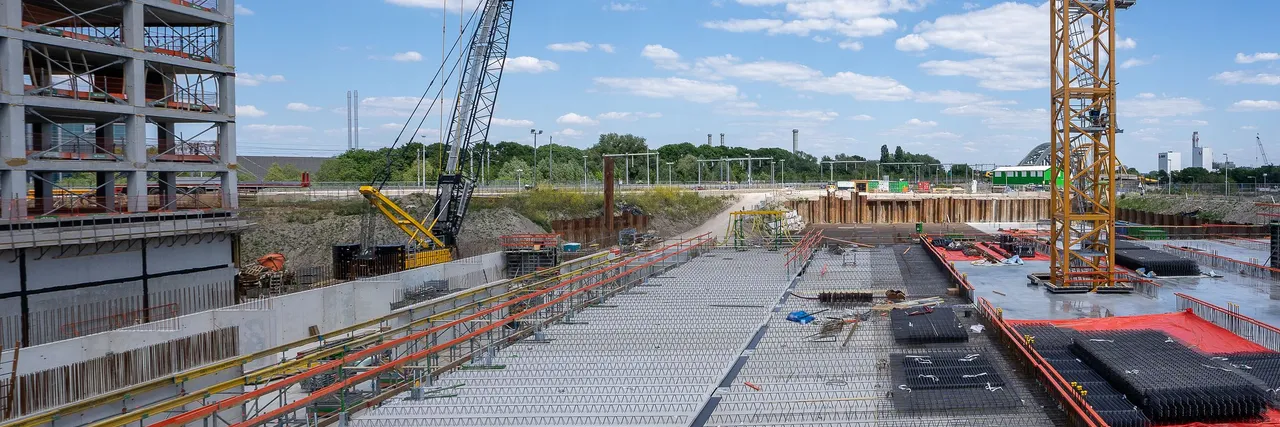 Construction cranes rising over a vast concrete deck at a large construction site