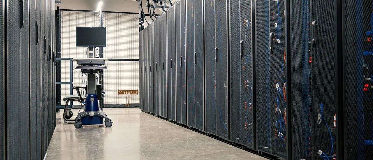 Rows of server racks lining a data hall aisle, with a monitoring cart at the far end