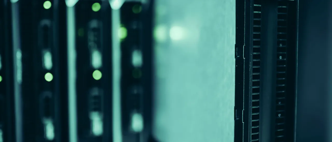 Close-up of dark blade servers in a rack, with rows of green status lights glowing in soft focus behind